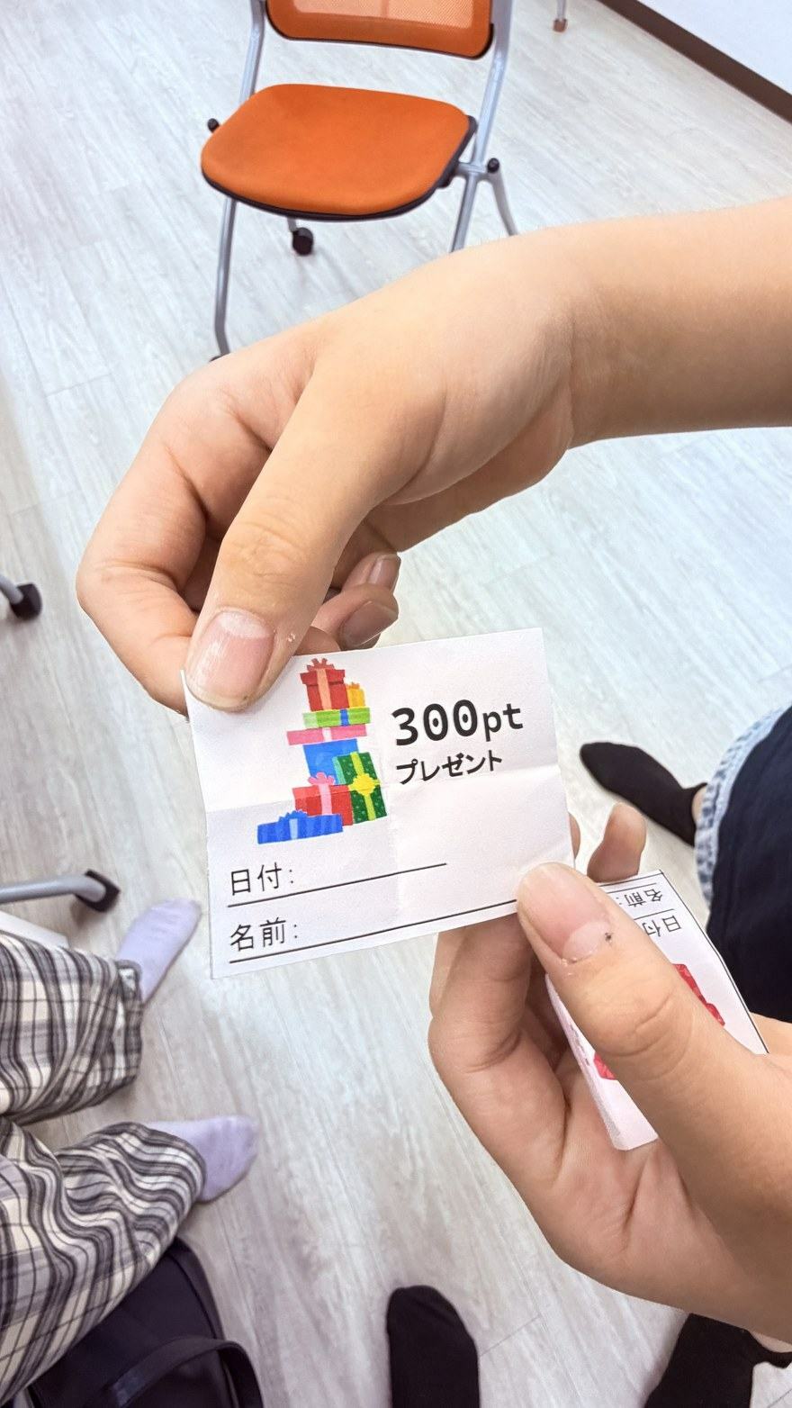 「300ptプレゼント」と書かれたカードを両手で持っているところ