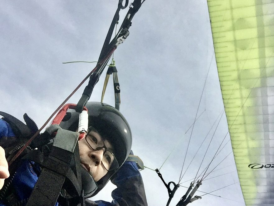 パラグライダーで飛行中の塾長。翼とラインが見える