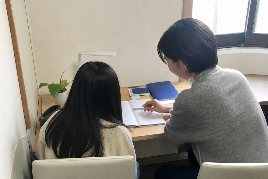 先生と生徒が並んでノートを見る子別の授業